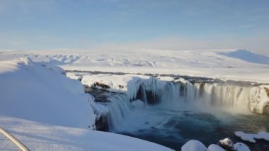 wide panning sunlit shot of godafoss waterfall and Skjalfandafljot river with snow and ice, iceland