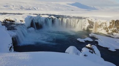 lockdown wide shot of sunlit godafoss waterfall and Skjalfandafljot river with snow and ice, iceland
