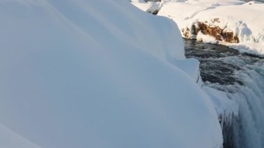 wide panning shot of sunlit godafoss waterfall and Skjalfandafljot river with snow and ice, iceland