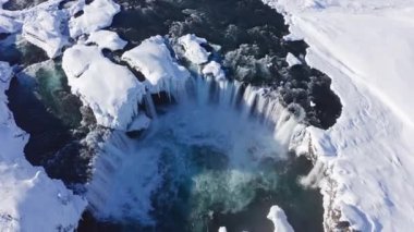 wide drone overhead of Skjalfandafljot river and godafoss waterfall in snow covered landscape, iceland
