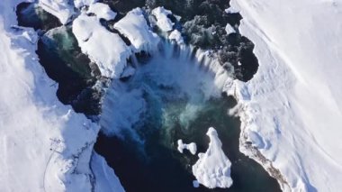 wide drone overhead of Skjalfandafljot river and godafoss waterfall in snow covered landscape, iceland