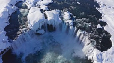 wide drone pulling back over Skjalfandafljot river and godafoss waterfall in snow covered landscape, iceland