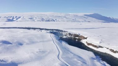 wide drone flight over Skjalfandafljot river and godafoss waterfall in snow covered landscape, iceland