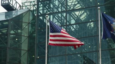 American National Flag Waving In Front a Modern Skyscraper Glass Facade. Slow Motion Shot