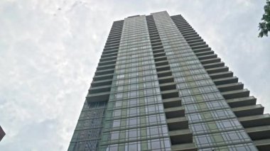 Wide Slow Motion Low Angle Shot Of Skyscraper And Tree Under Cloudy New York Sky