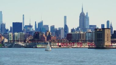 Sailboat in Front of Modern High Rising Glass Buildings of Manhattan, New York. Trucking Left Panoramic Shot