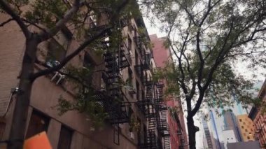 Typical New York Style Emergency Fire Escape Stairs Outside Residential Building. Fire Escape Ladder. Bottom View Through the Trees