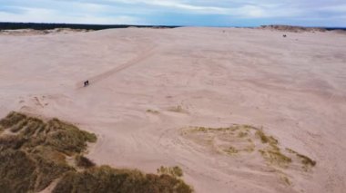 Aerial Panoramic Wide Shot Of Tourists Walking on Sand Dunes Towards the Horizon. Camera Zooms In and Moves Forwards