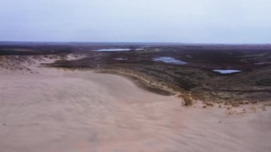 Aerial Wide Side View Shot Of a Tourist Standing on a Top of a Sand Dune and Enjoying the View. Camera Flies Over the Tourist and Moves Backwards