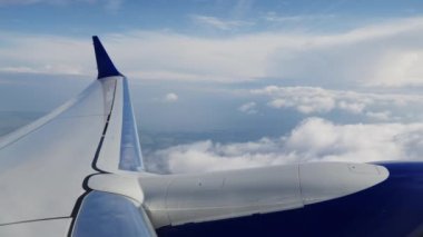 View Through Plane Window on an Aircrafts Wing, Engine and Passing By Clouds During the Flight. Beautiful Scenery Outside the Window