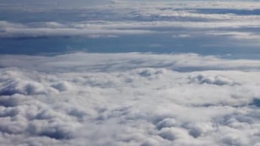 View Through Plane Window on a Blue Sky and Sea of Clouds During the Flight. Beautiful Scenery Outside the Window