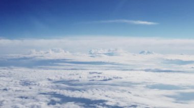 View Through Plane Window on a Blue Sky and Sea of Clouds During the Flight. Beautiful Scenery Outside the Window