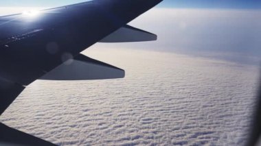 Close-up View Through Plane Window on Aircrafts Wing and Sea of White Clouds Underneath During the Flight. Beautiful Scenery Outside the Window