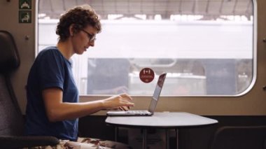 Woman with Curly Hairs and with Glasses On Working on a Laptop While Waiting for the Train Departure