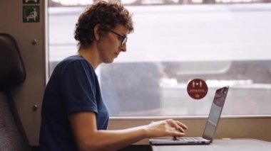 Portrait of a Woman with Curly Hairs and with Glasses On Working on a Laptop While Waiting for the Train Departure