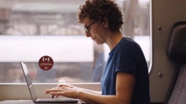 Portrait of a Woman with Curly Hairs and with Glasses On Working on a Laptop While Waiting for the Train Departure