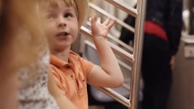 Portrait of a Little Blond Haired Boy Rides Subway. He Sits Inside the Metro Coach and Says Something. Slow Motion Shot