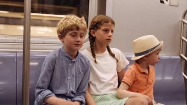 Girl with Two Younger Brothers Ride Subway. They Sit Inside the Metro Coach and Talk to Each Other. Slow Motion Shot