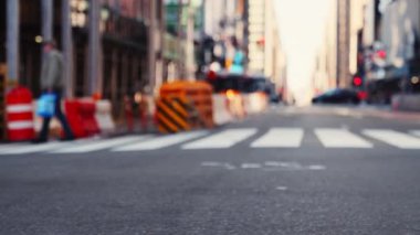 Zebra Crossing with a Few Pedestrians on the Road of Midtown New York. Car Is Passing By the Camera.  Defocused Cityscape. Slow Motion Low Angle Trucking Shot