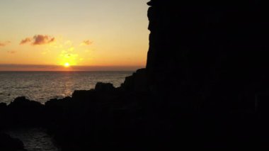 Aerial View of a Cliff Silhouette at Seacoast on Bornholm Island at Golden Sunset, Denmark. Camera Moves Up Along the Cliff
