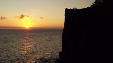 Aerial View of a Cliff Silhouette at Seacoast on Bornholm Island at Golden Sunset, Denmark. Camera Moves Up Along the Cliff