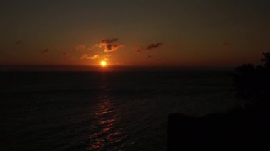 Aerial Over Calm Sea at Bornholm Island at Orange Sunset. Stunning Seascape. Camera Moves Down Along the Cliff Silhouette. Panoramic Shot