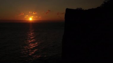Aerial Over Calm Sea at Bornholm Island at Orange Sunset. Stunning Seascape. Camera Moves Up Along the Cliff Silhouette. Panoramic Shot