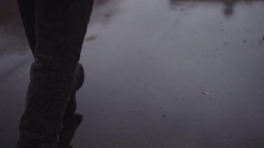 Mans Feet in Leather Shoes Walking on Wet Asphalt Road at the Rain. Slow Motion Shot. Camera Follows the Man