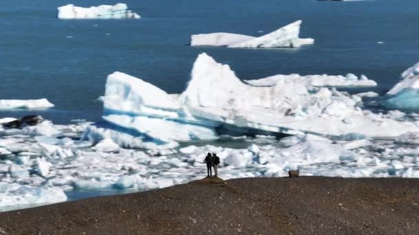 Aerial Two Tourists Standing Top Hill Front Jokulsarlon Lagoon Iceland — Wideo stockowe