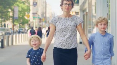 Medium Slow Motion Tracking Shot Of Mother Walking Hand In Hand With Her Two Sons Through New York City Streets