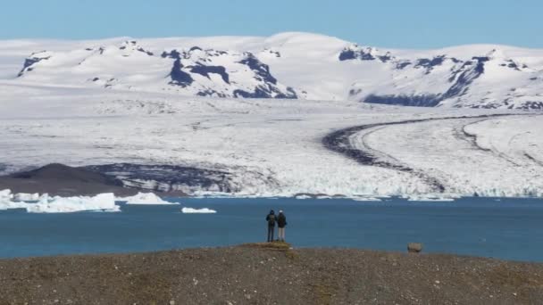 Aerial Two Tourists Standing Top Hill Front Jokulsarlon Lagoon Iceland — Vídeo de Stock