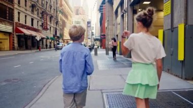 Tracking Medium Slow Motion Handheld Shot Of Brother And Sister Walking Together Along New York City Street