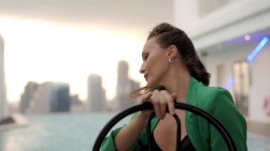 Medium Slow Motion Handheld Tracking Shot Of Sensuous Dancer Posing To Camera In Bra And Green Jacket At Poolside