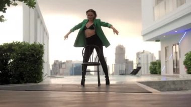 Wide Slow Motion Dolly Shot Of Sensuous Dancer Standing And Moving By Chair In High Heels And Bra At Poolside