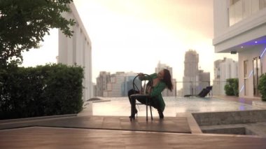 Lockdown Wide Slow Motion Shot Of Sensuous Woman Crouching And Dancing In High Heels And Bra With Chair At Poolside