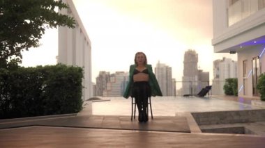 Wide Slow Motion Lockdown Shot Of Young Woman In Bra And High Heels Sitting And Dancing On Poolside Chair
