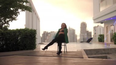 Wide Slow Motion Lockdown Shot Of Young Woman In Bra And High Heels Sitting And Dancing On Poolside Chair