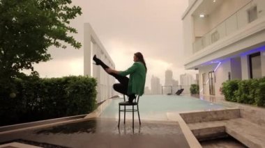 Slow Motion Wide Zoom Out Of Dancer Posing And Stepping From Chair At Poolside
