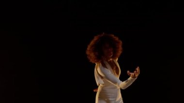 Portrait of Smiling African American Woman with Afro Style Hairs in White Jumpsuit Wearing Roller Scates Dancing on the Stage Under Shiny Disco Ball. Cinematic Slow Motion Shot