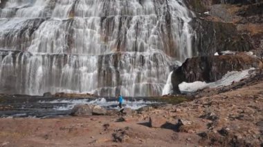 Wide Tracking Slow Motion Shot Of Man Walking Over Rocks In Front Of Dynjandi Waterfall, Arnarfjordur, Westfjords, Iceland