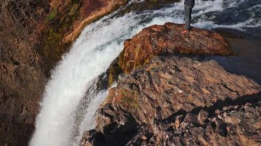 Wide Tilt Up Slow Motion Shot Of Photographer Standing On Rocks Over Dynjandi Waterfall, Arnarfjordur, Westfjords, Iceland