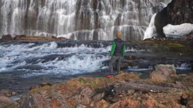 Wide Zoom In Slow Motion Shot Of Man Standing On Rocks And Looking Up At The Dynjandi Waterfall, Arnarfjordur, Westfjords, Iceland