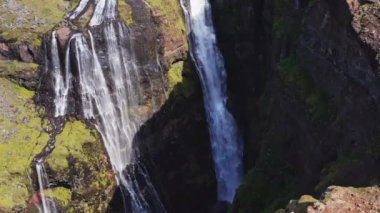 Aerial View of Majestic Glymur Waterfall In West Iceland on a Bright Sunny Day. Unique Nature of Iceland. High Angle Shot. Camera Moves Upwards