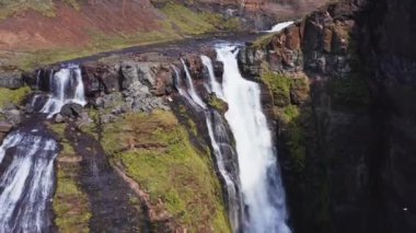 Aerial View of Majestic Glymur Waterfall In West Iceland on a Bright Sunny Day. Unique Nature of Iceland. Tilt Down Shot. Camera Moves Backwards