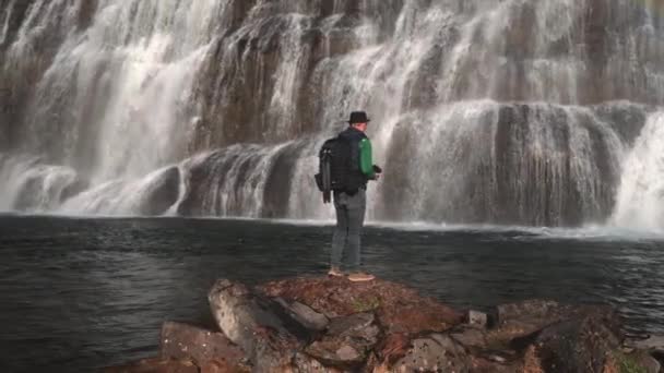 Wide Slow Motion Arcing Shot Photographer Backpack Standing Rock River — Video