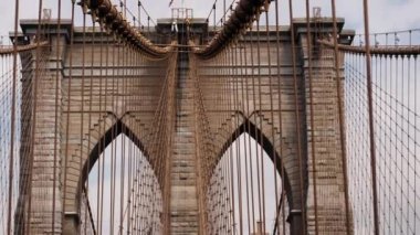 Close-up of Brooklyn Bridge Towers with American National Flag on the Top and Cables of the Bridge. Tilt Up Shot
