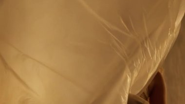 Close-up of a Professional Dancer Performing in Studio in Soft Warm Lighting. Graceful Young Woman with Long Hairs Dancing with White Stage Curtain. Slow Motion Shot