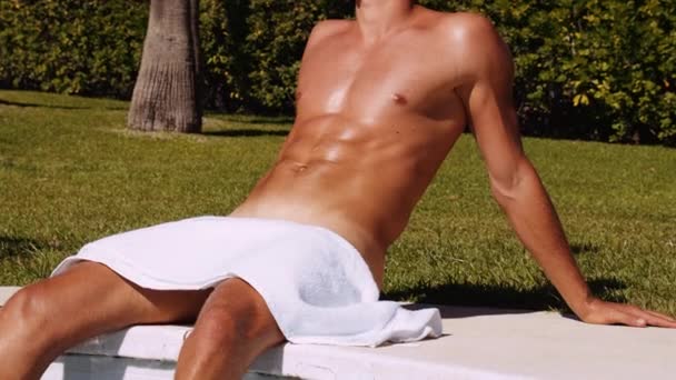 Medium Slow Motion Shot Tilting Muscular Tanned Man Sitting Poolside — Stockvideo