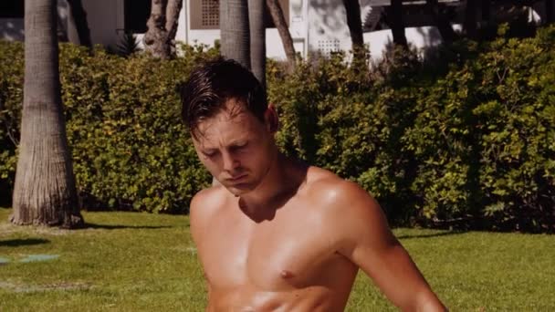 Medium Slow Motion Shot Tilting Muscular Tanned Man Sitting Poolside — 图库视频影像