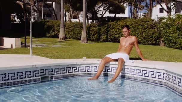 Medium Slow Motion Shot Tilting Muscular Tanned Man Sitting Poolside — Stockvideo